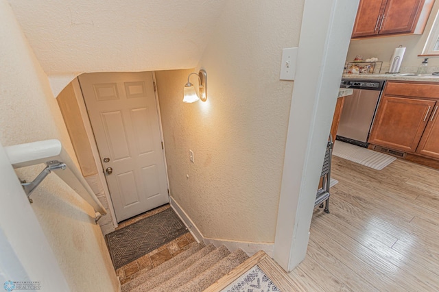 stairs with baseboards, wood finished floors, and a textured wall