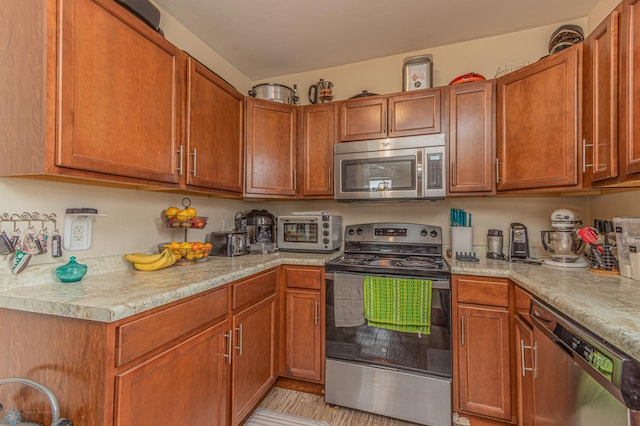 kitchen with stainless steel appliances, a toaster, brown cabinetry, and light countertops