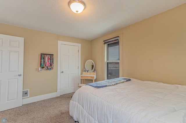 bedroom featuring visible vents, a textured ceiling, baseboards, and carpet