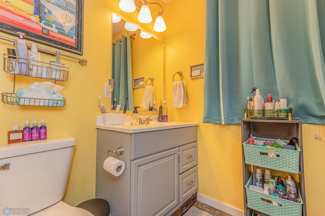 bathroom with baseboards, toilet, and vanity