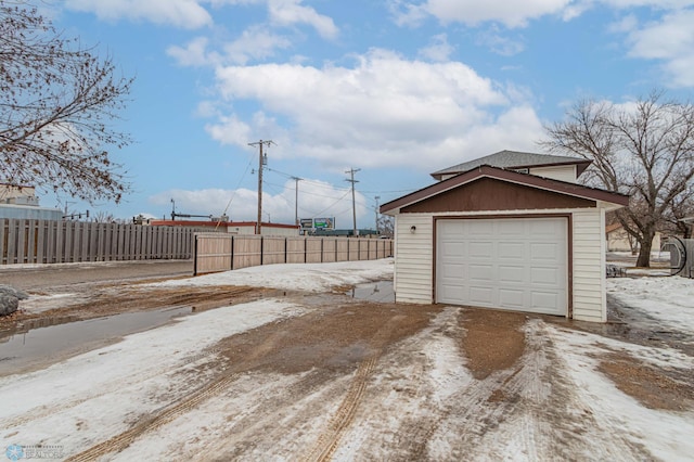 snow covered garage featuring fence