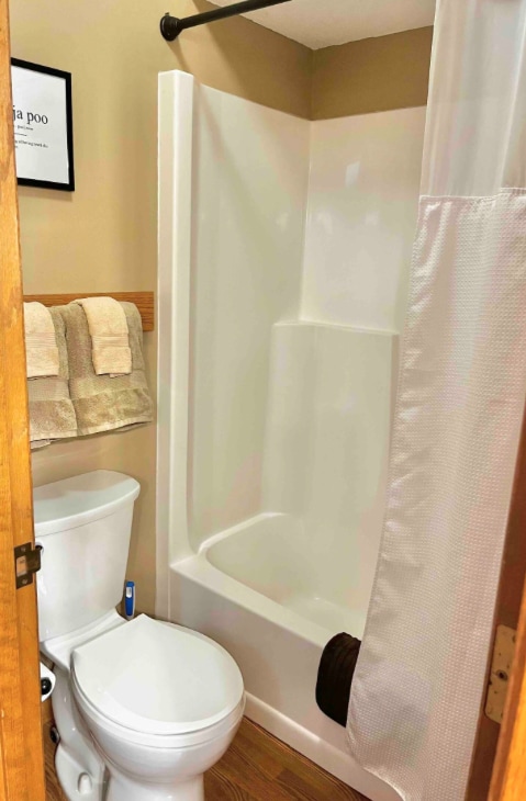 bathroom with toilet, shower / bath combo, and wood finished floors