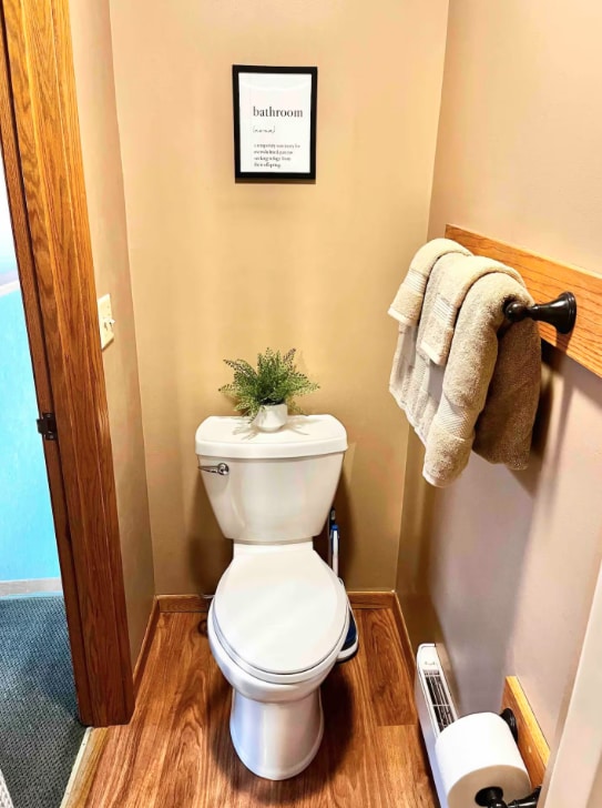 bathroom with a baseboard radiator, baseboards, toilet, and wood finished floors