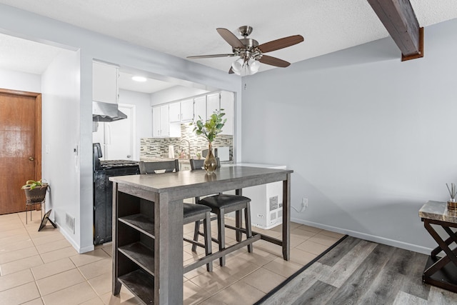 kitchen with visible vents, decorative backsplash, white cabinets, black range with gas cooktop, and under cabinet range hood