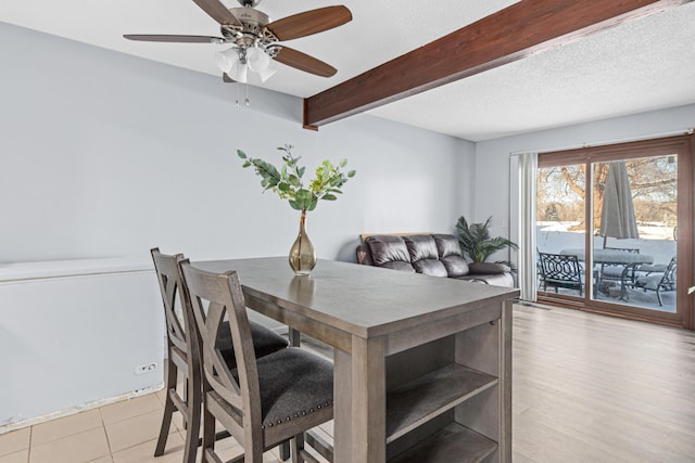 dining space featuring a textured ceiling, light wood finished floors, beamed ceiling, and a ceiling fan