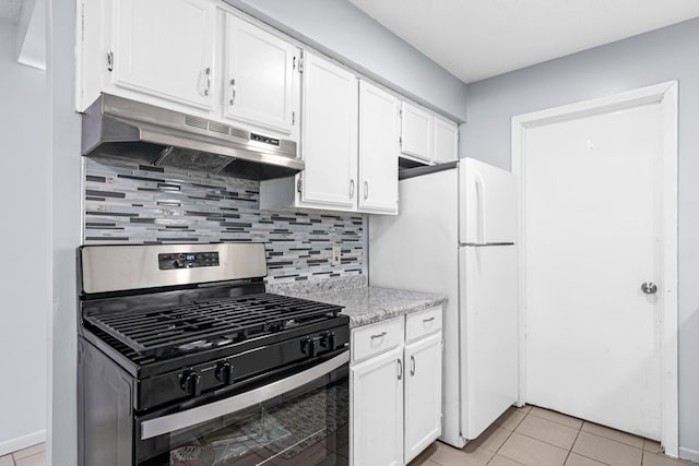 kitchen featuring light tile patterned floors, under cabinet range hood, white cabinets, freestanding refrigerator, and stainless steel gas stove