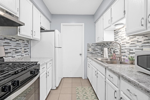 kitchen with light tile patterned floors, white microwave, under cabinet range hood, a sink, and black gas stove