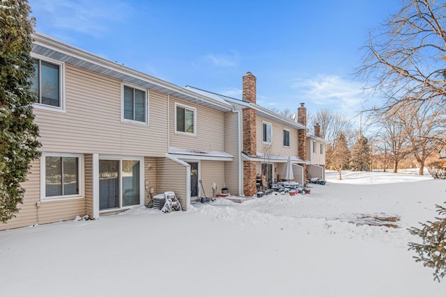 snow covered house featuring a chimney