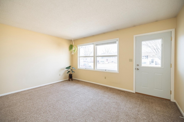 carpeted entryway with a textured ceiling and baseboards