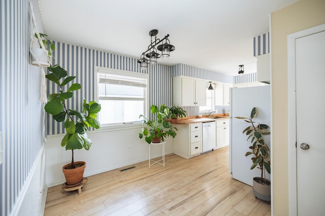 kitchen featuring white appliances, butcher block counters, white cabinets, light wood-type flooring, and a chandelier