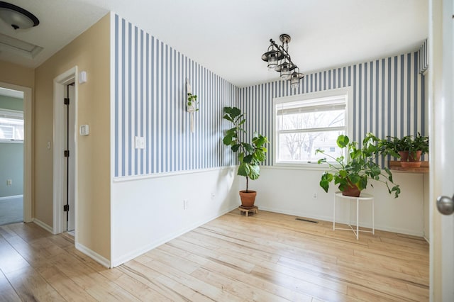 interior space featuring visible vents, wallpapered walls, baseboards, and wood finished floors