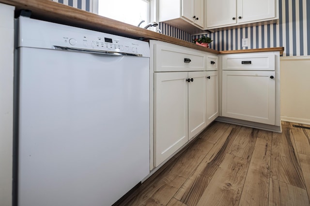 kitchen with visible vents, wallpapered walls, dishwasher, wood finished floors, and white cabinetry