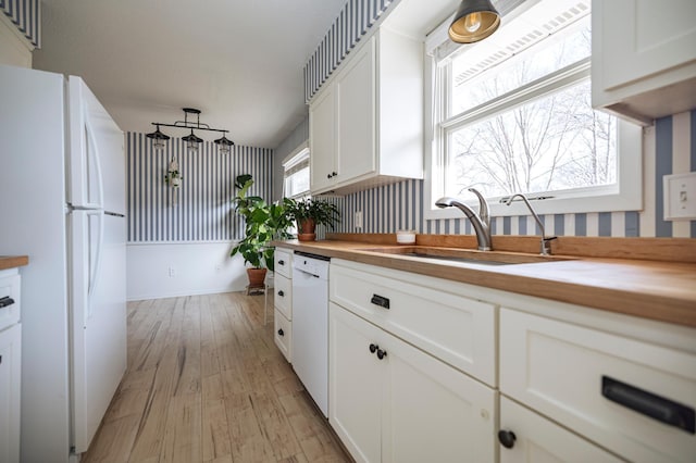 kitchen featuring white appliances, light wood-style flooring, a sink, white cabinets, and wood counters