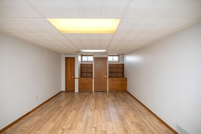 empty room with visible vents, baseboards, light wood-style floors, and stairway