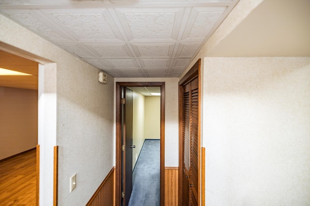 hallway featuring wainscoting, an ornate ceiling, and wood finished floors