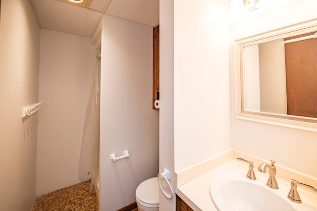 full bathroom featuring vanity, a shower with shower curtain, toilet, and a drop ceiling