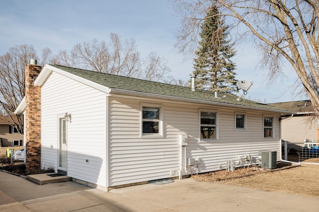 rear view of property with central AC unit, a chimney, and a patio area