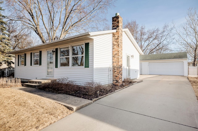 view of front of home featuring a chimney, a garage, and an outdoor structure