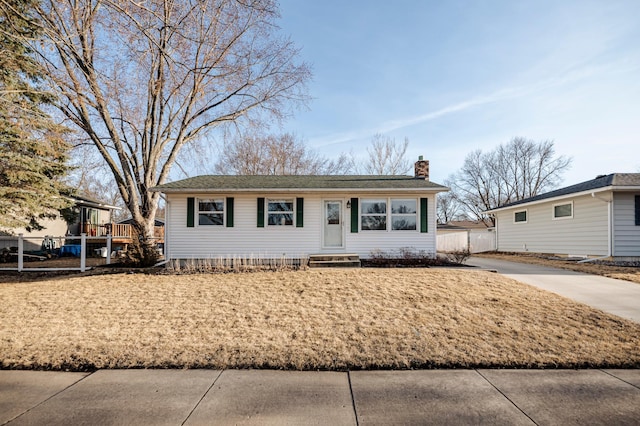 view of front of home featuring driveway, entry steps, a chimney, and fence