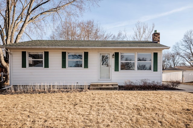 view of front facade featuring a front lawn, a chimney, and entry steps