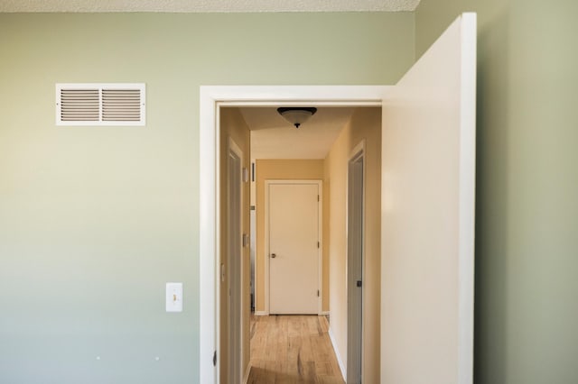 hall featuring visible vents and light wood finished floors