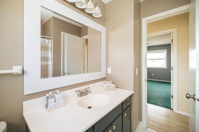 full bathroom with baseboards, wood finished floors, and vanity