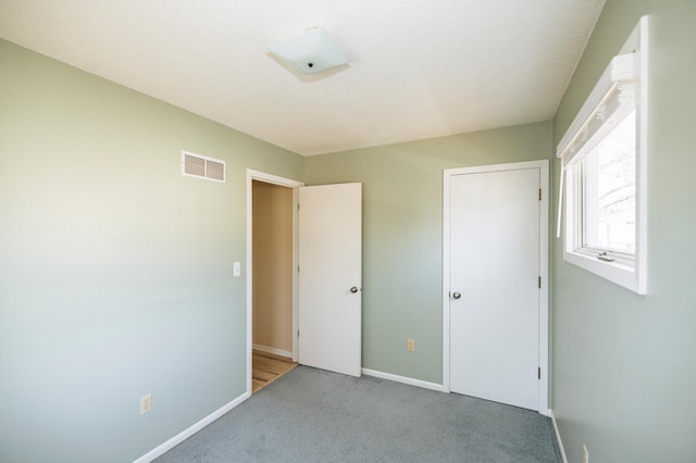 unfurnished bedroom with visible vents, carpet flooring, and baseboards