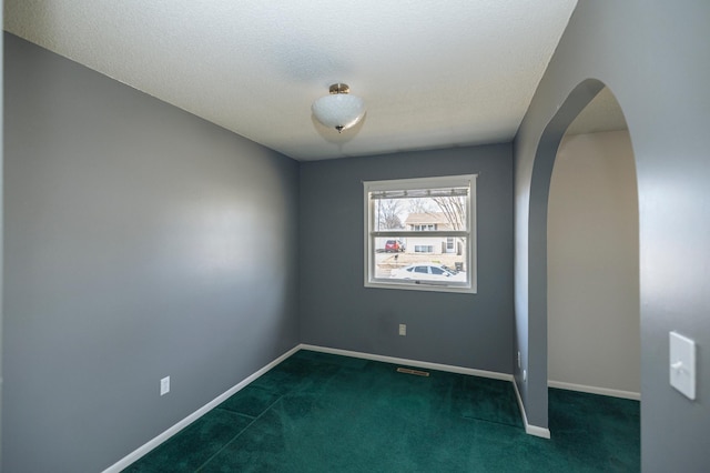 empty room with baseboards, arched walkways, carpet floors, and a textured ceiling