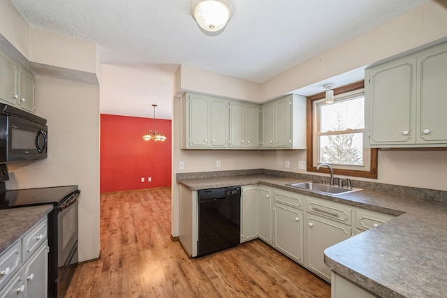 kitchen with a sink, dark countertops, black appliances, and light wood finished floors