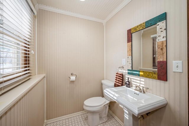 half bath featuring baseboards, a sink, crown molding, toilet, and tile patterned floors