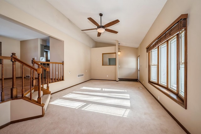 carpeted spare room featuring vaulted ceiling, baseboards, visible vents, and ceiling fan