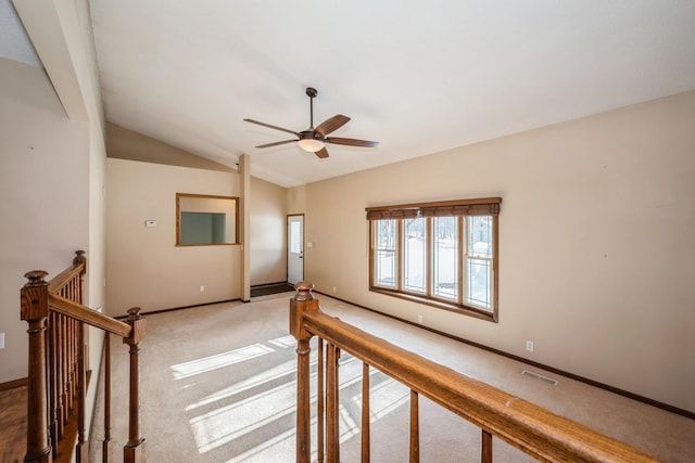 interior space featuring visible vents, an upstairs landing, baseboards, light colored carpet, and vaulted ceiling