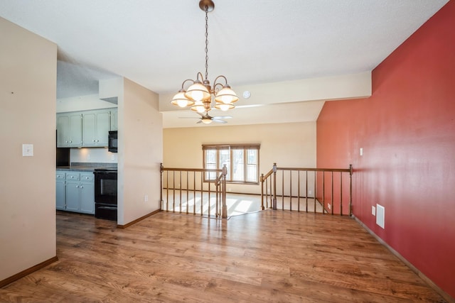 unfurnished dining area featuring a notable chandelier, baseboards, and wood finished floors