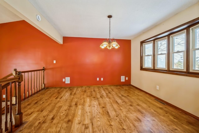 empty room featuring lofted ceiling with beams, light wood-type flooring, visible vents, and a chandelier