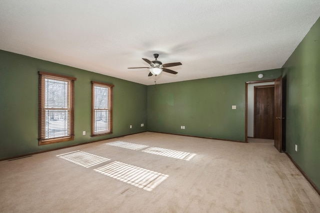 unfurnished room with visible vents, baseboards, light carpet, a textured ceiling, and a ceiling fan