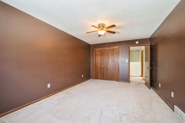 unfurnished bedroom featuring visible vents, ceiling fan, carpet flooring, a closet, and a textured ceiling