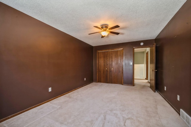 unfurnished bedroom featuring visible vents, ceiling fan, carpet flooring, a closet, and a textured ceiling