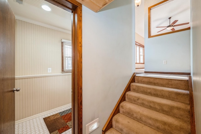 staircase with visible vents, baseboards, ceiling fan, and crown molding