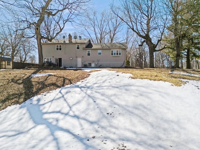 snow covered rear of property with a chimney