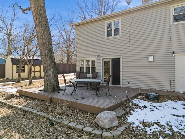 back of house featuring an outbuilding, fence, a wooden deck, outdoor dining area, and a storage shed