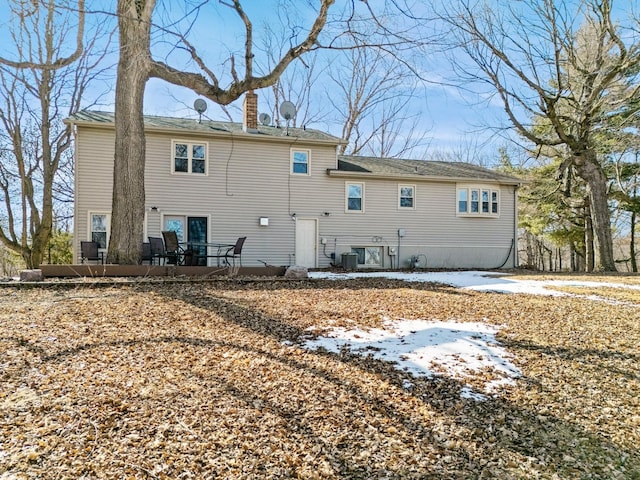 rear view of property featuring central air condition unit and a chimney