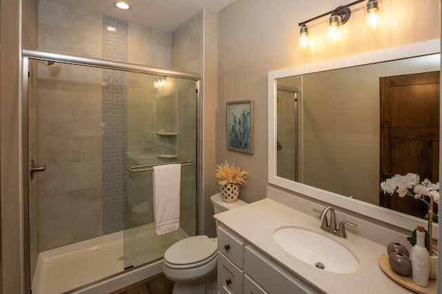 bathroom with a stall shower, vanity, and toilet