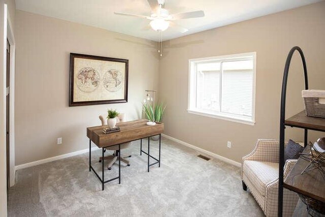 office space featuring light carpet, visible vents, baseboards, and a ceiling fan