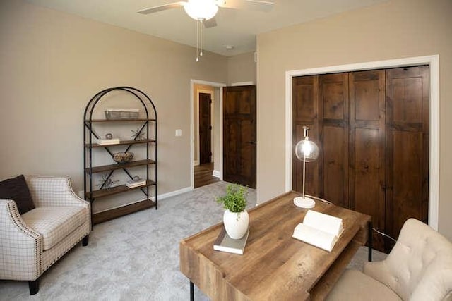 living area featuring light colored carpet, ceiling fan, and baseboards