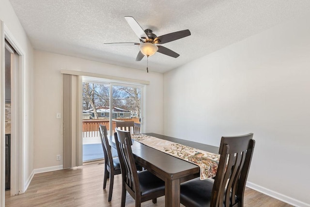 dining area with a textured ceiling, a ceiling fan, light wood-style flooring, and baseboards