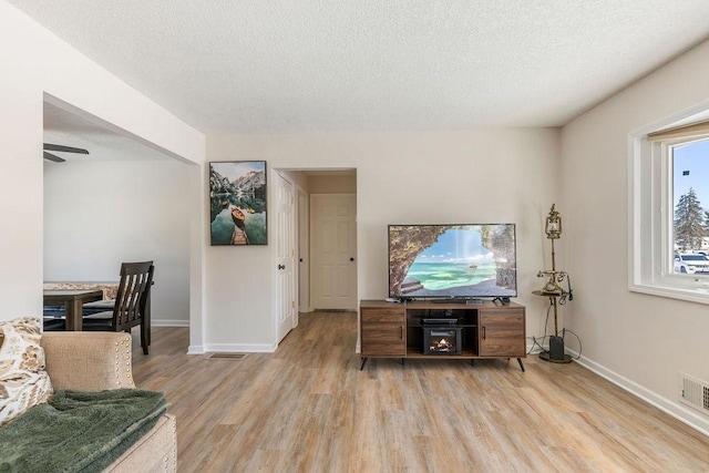 living room featuring light wood-style flooring, baseboards, and a textured ceiling