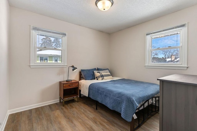 bedroom featuring a textured ceiling, wood finished floors, and baseboards