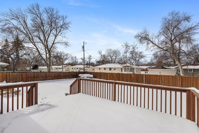 snow covered deck featuring a fenced backyard and a residential view