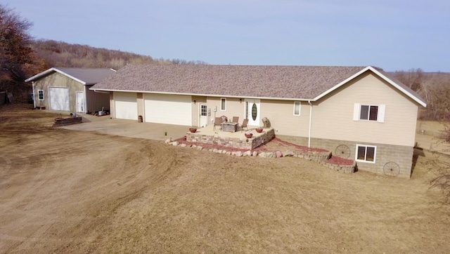 ranch-style house featuring a patio area, driveway, an attached garage, and roof with shingles