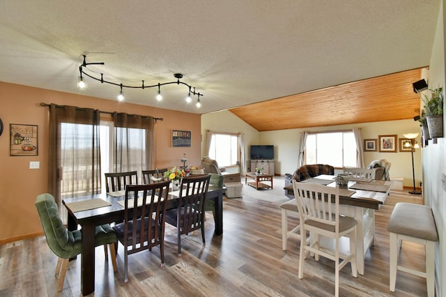 dining room featuring wood finished floors, vaulted ceiling, rail lighting, a textured ceiling, and wooden ceiling